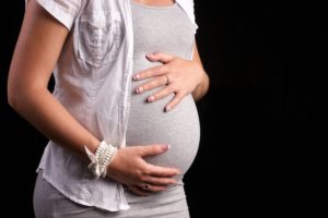 Беременная женщина держит живот
